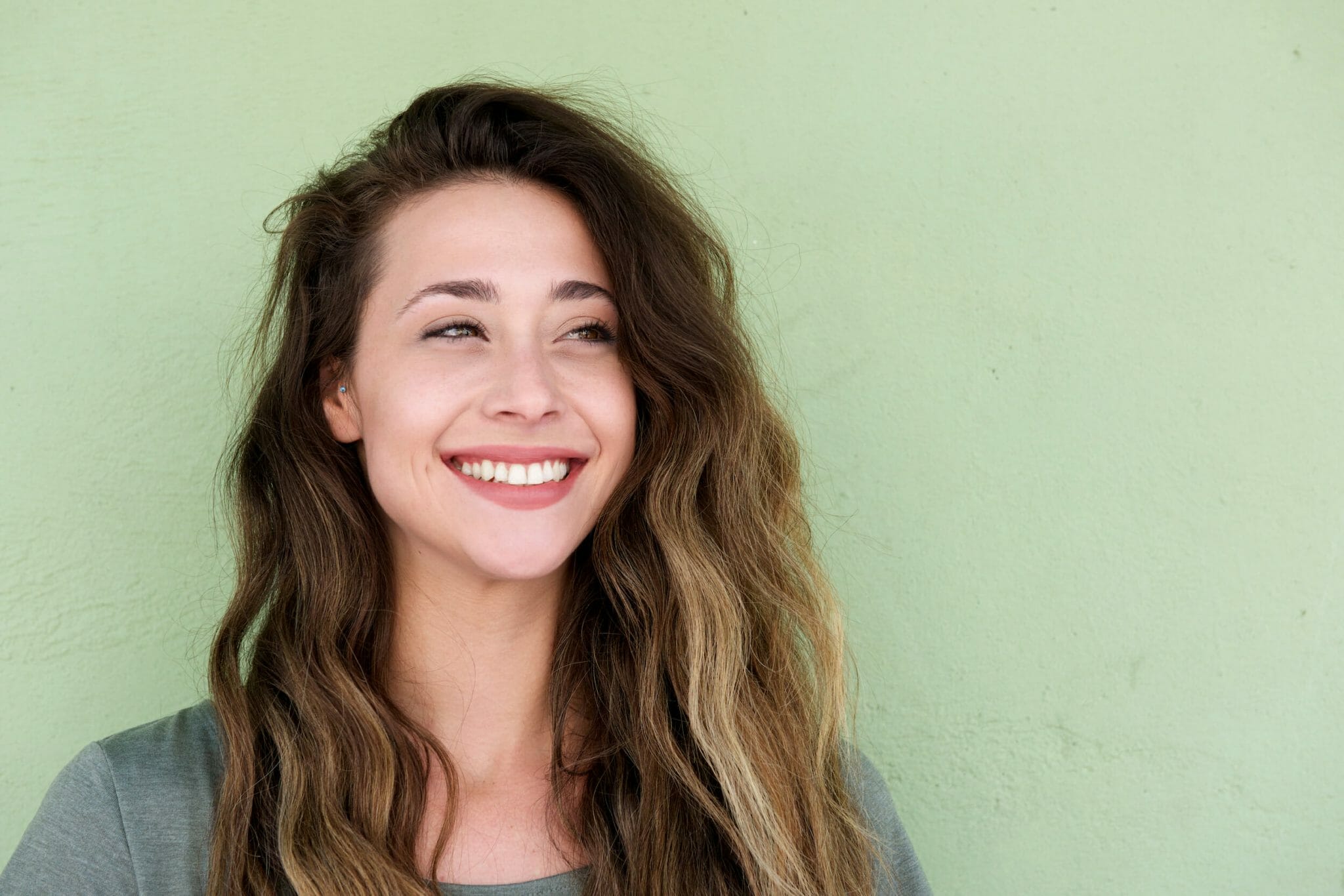 young beautiful woman on green background smiling